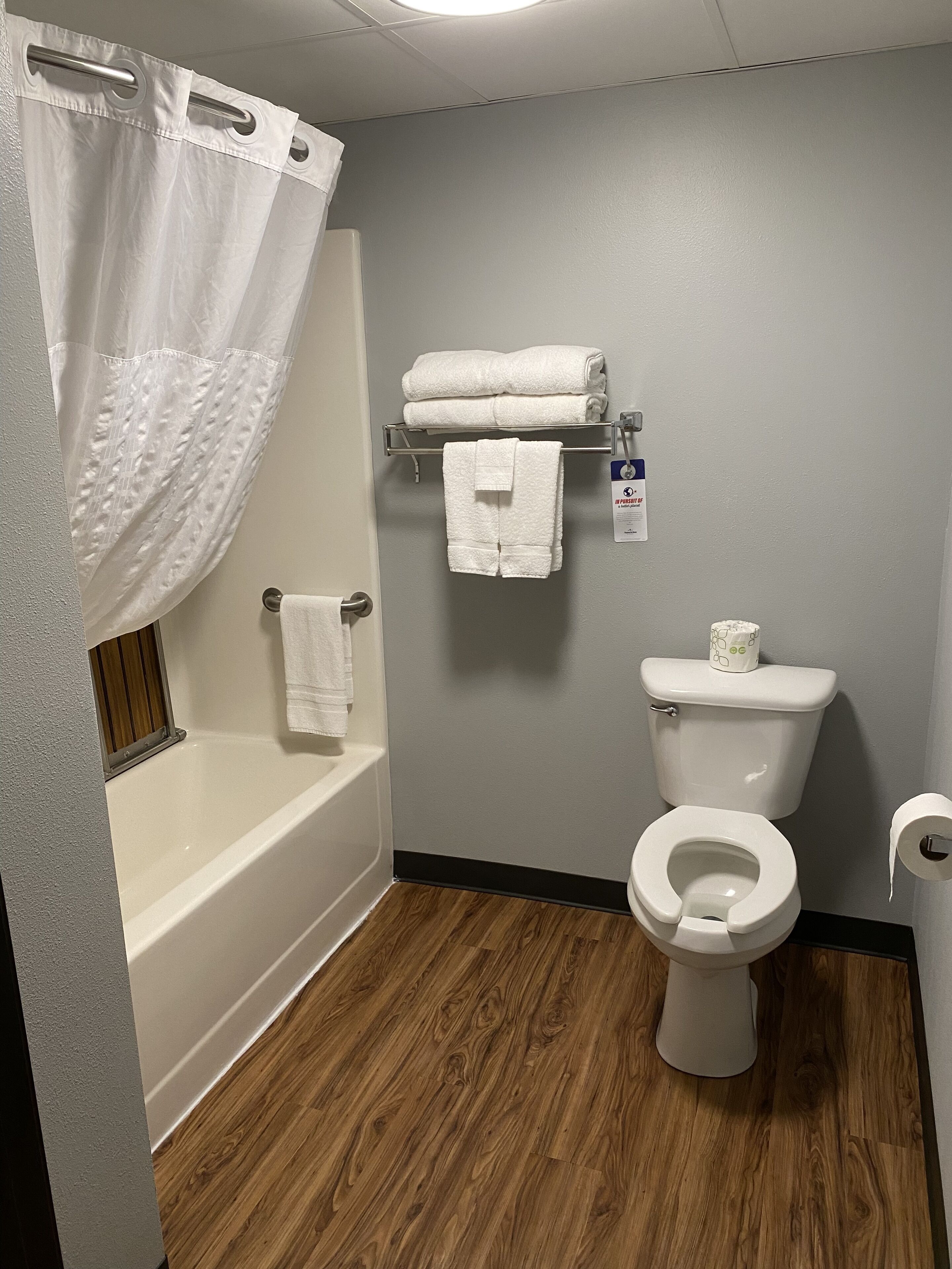 A bathroom with a bathtub, toilet, and a towel rack.