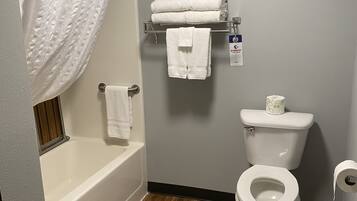 A bathroom with a bathtub, toilet, and a towel rack.
