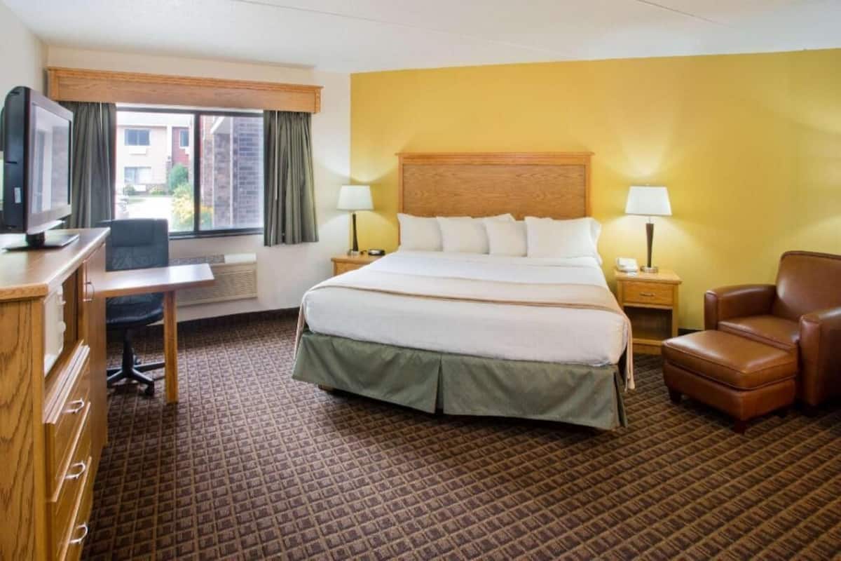 A hotel room with a bed, desk, chair, and a television.