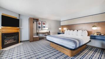 Et hotelværelse med en stor seng, pejs, skrivebord og fjernsyn.
