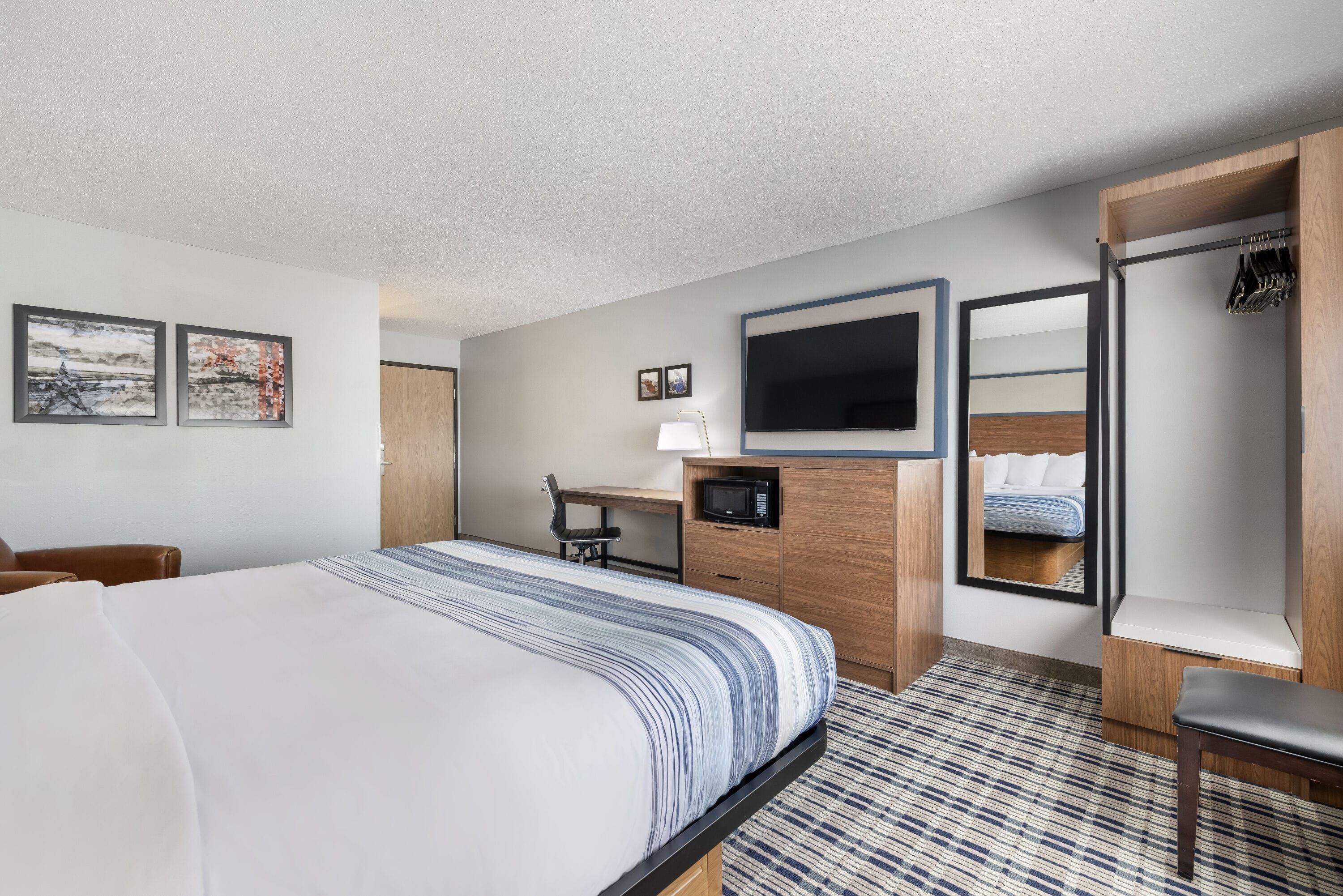 Ein Hotelzimmer mit Bett, Schreibtisch, Stuhl, Fernseher und Kleiderschrank.