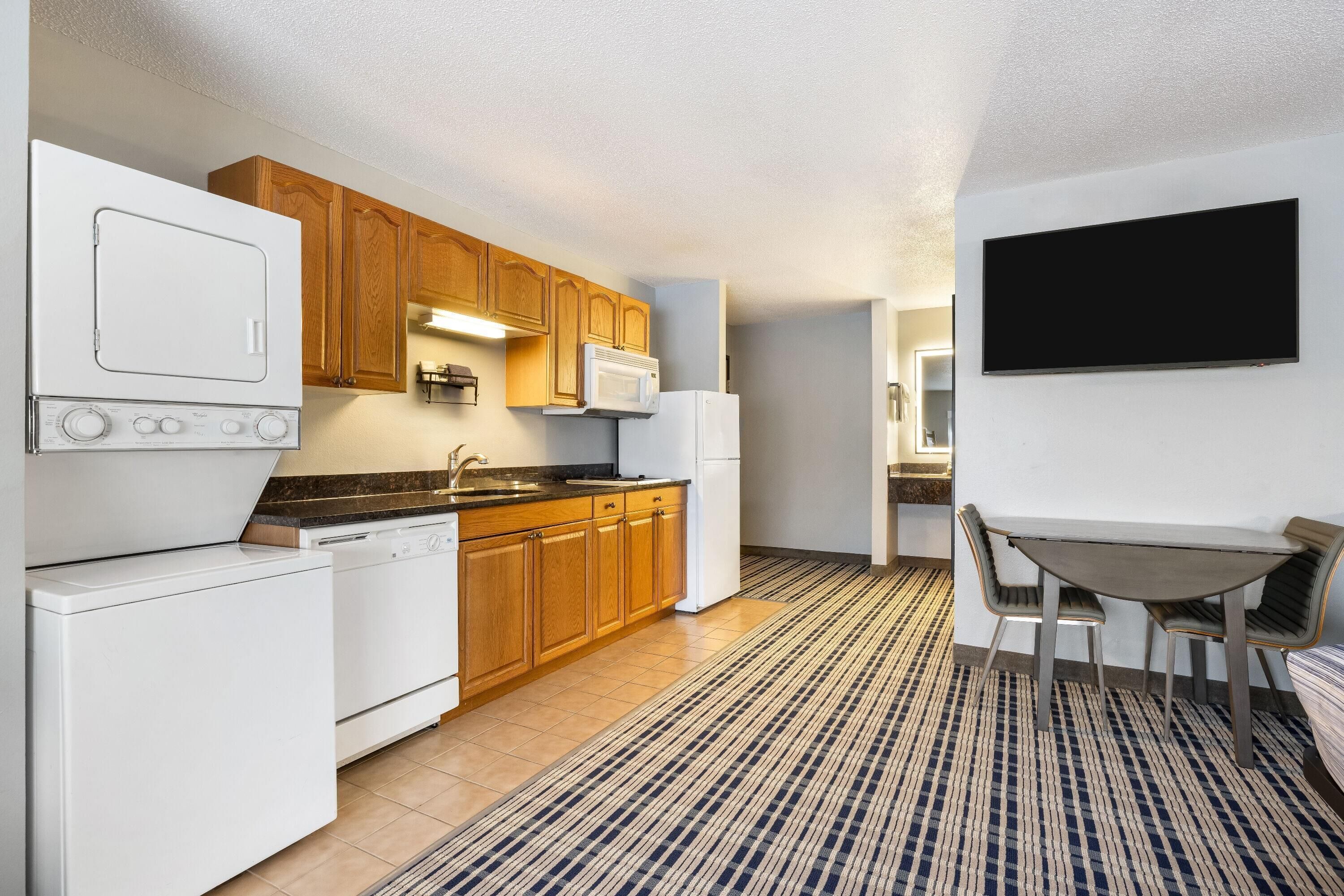 A compact kitchen with wooden cabinets, a microwave, a dishwasher, and a built-in oven.