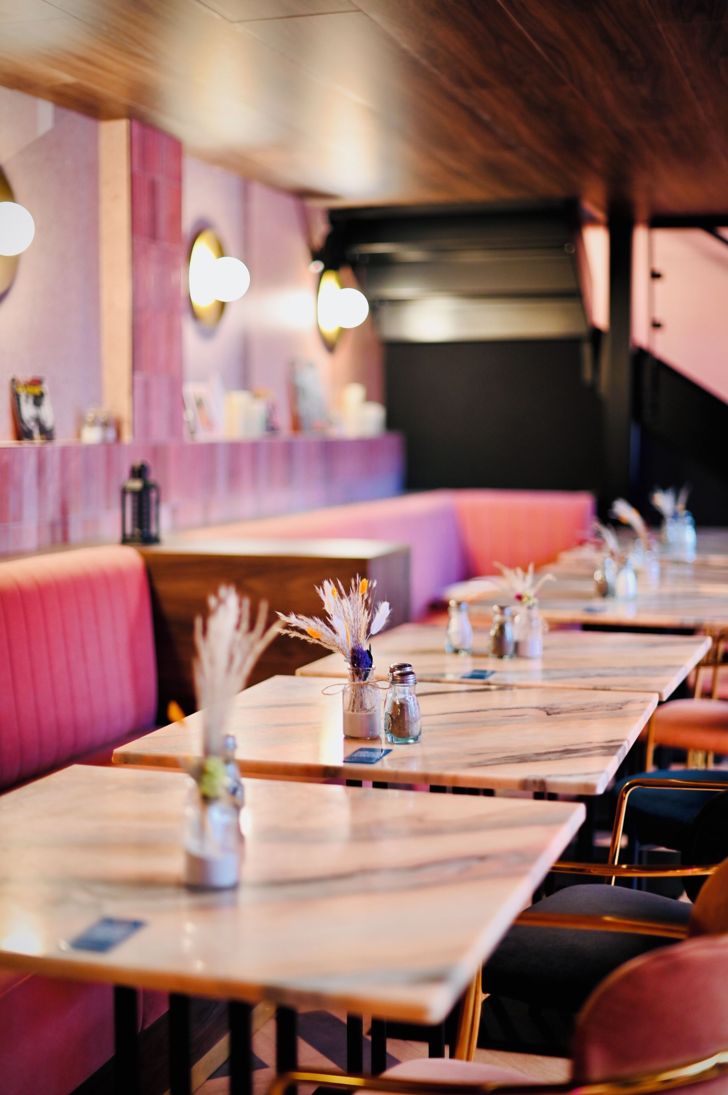 Ein Restaurant mit Sitzgelegenheiten in Form von Stellplätzen und Tischen, jeweils mit einer Blumenvase und Salz- und Pfefferstreuern.