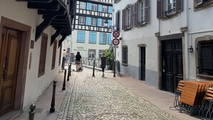 A cobblestone street lined with traditional half-timbered buildings, a sign for 'Pavilion Régent Petite France', and a no-parking sign. - ClapClap Hôtel Strasbourg (Strasbourg)
