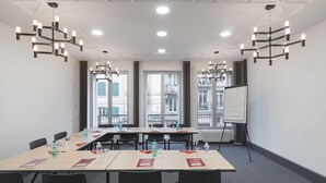A conference room with a long table, black chairs, water bottles, nameplates, and a whiteboard. - ClapClap Hôtel Strasbourg (Strasbourg)