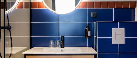 Un baño con lavamanos, espejo e inodoro.