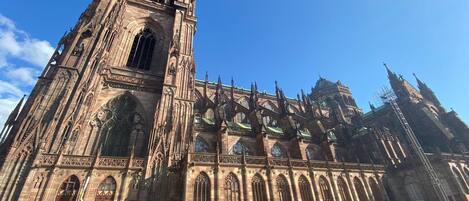 Una gran catedral gótica con una alta torre central y múltiples ventanales de arco.