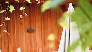 Outdoor seating with tables and chairs, a white umbrella, and a wooden wall in the background. - ClapClap Hôtel Strasbourg (Strasbourg)