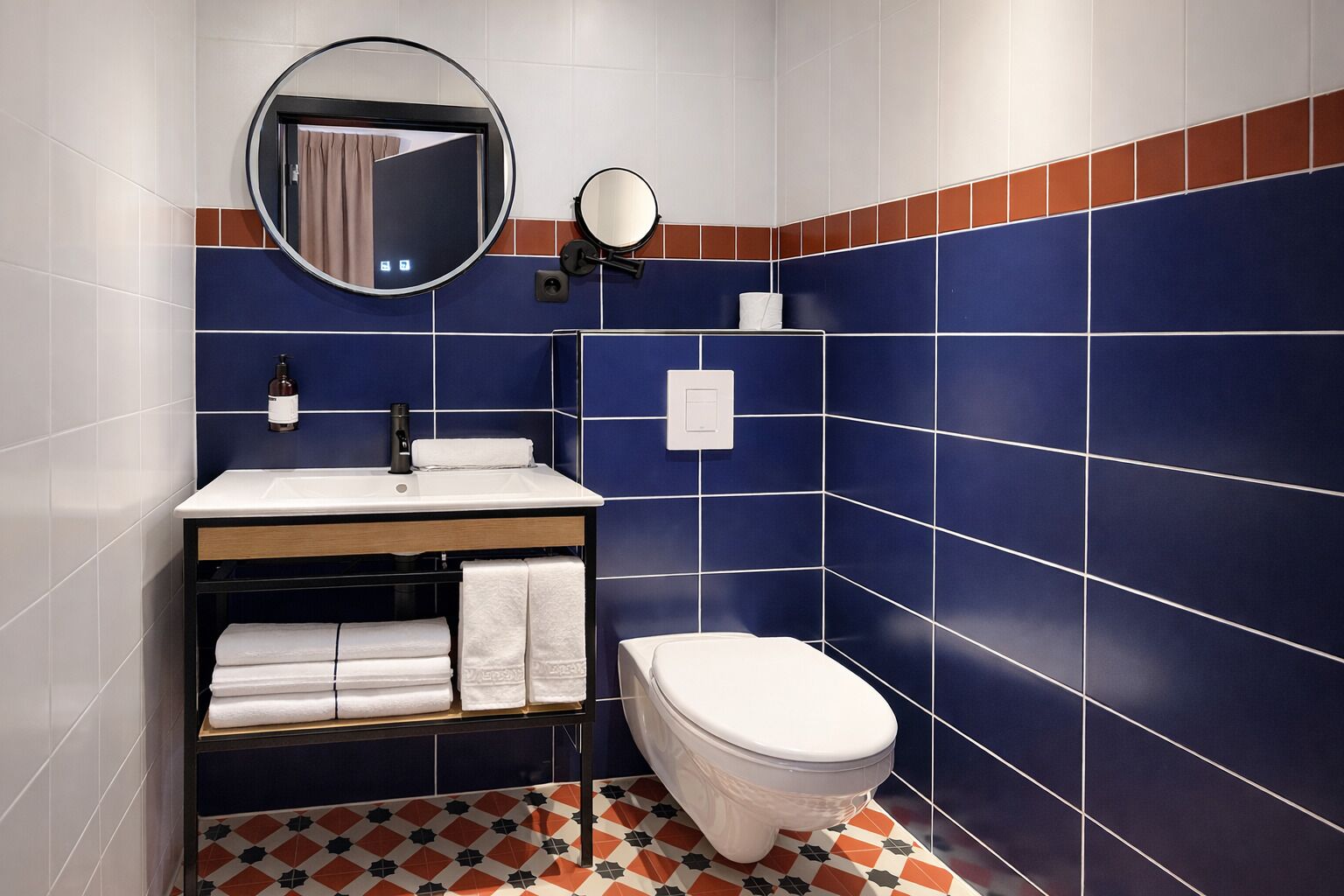 A bathroom with a white sink, a mirror, a toilet, and blue-tiled walls.