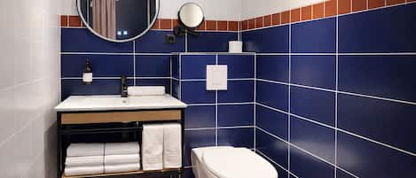 A bathroom with a white sink, a mirror, a toilet, and blue-tiled walls.