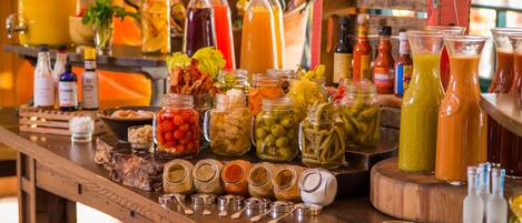 A bar area with various beverages, including juices, sodas, and cocktails, and a selection of condiments and spices.