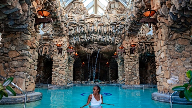 A pool with a woman in the center, surrounded by stone walls and waterfalls. - The Omni Grove Park Inn & Spa (Asheville)