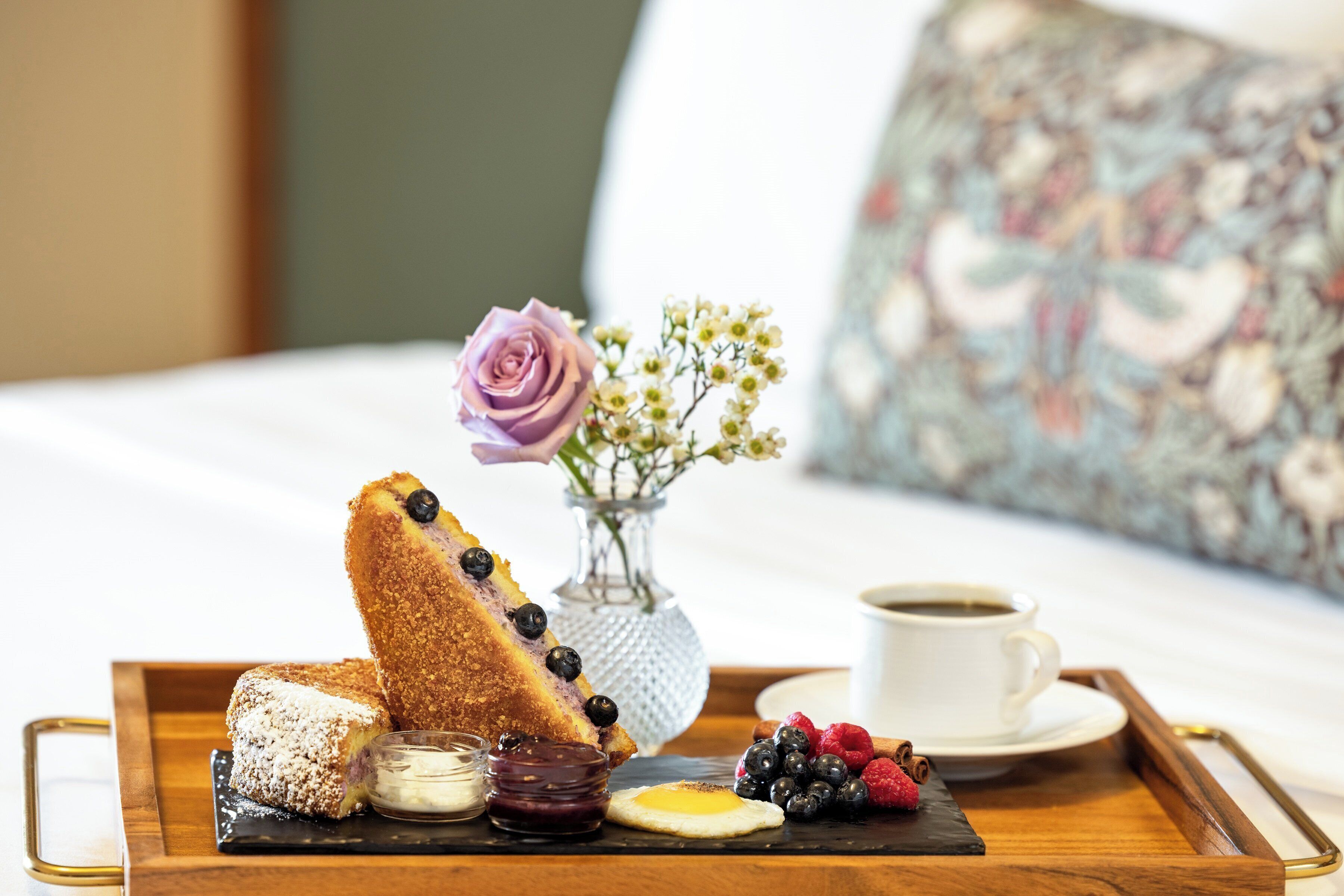 A breakfast tray with toast, jam, a cup of coffee, and fresh berries.