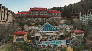 A hotel with a stone facade, a swimming pool, and multiple red-roofed buildings in the background. - The Omni Grove Park Inn & Spa (Asheville)
