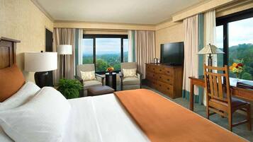 Habitación de hotel con una cama grande, un escritorio con silla, televisión, cómoda y vistas al exterior.