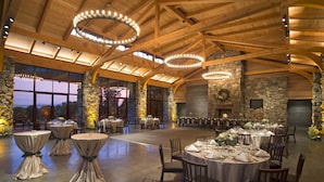 A spacious hall with high wooden ceilings and stone walls, featuring round tables set for dining. - The Omni Grove Park Inn & Spa (Asheville)