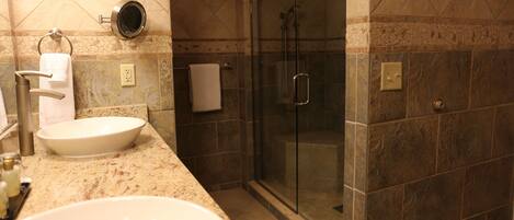 A bathroom with a large sink, a glass shower enclosure, and a towel rack.