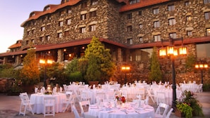 A stone building with multiple dining tables set for an event. - The Omni Grove Park Inn & Spa (Asheville)