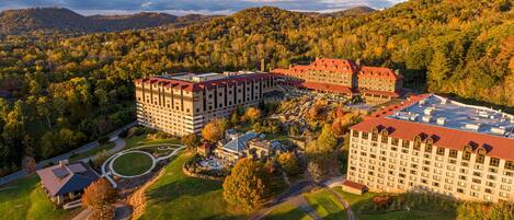 A large hotel complex with multiple buildings, surrounded by lush greenery and hills.