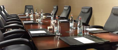 A conference room with a long table, black leather chairs, water bottles, and nameplates.