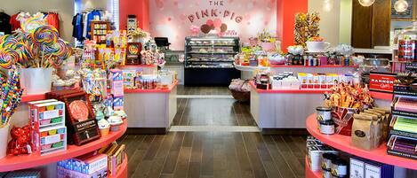 Een snoepwinkel met een roze thema, met snoeprekken, een display van lolly's en een bord waarop staat