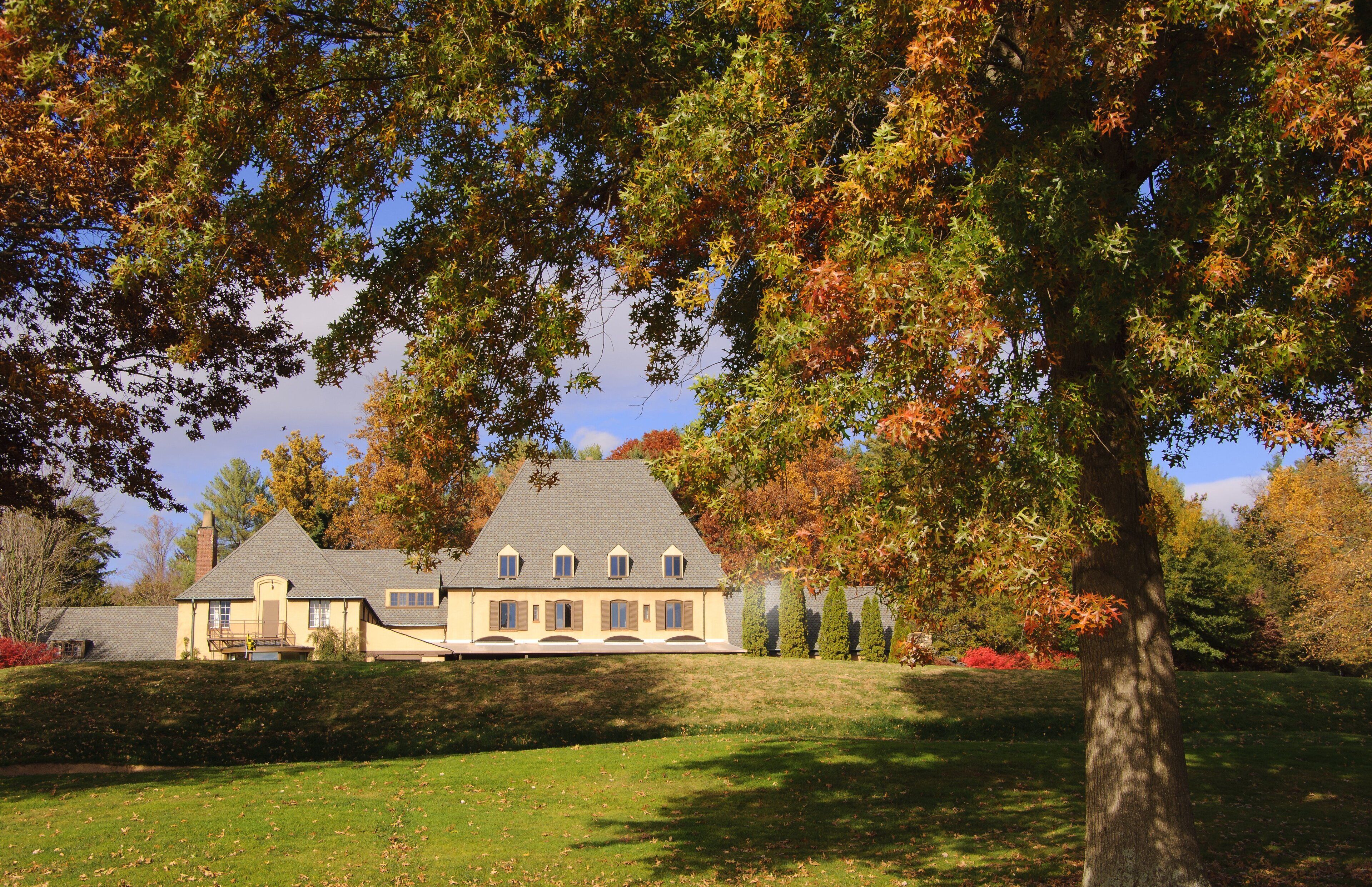 Une grande maison à deux étages, dotée d’un toit en pente et de nombreuses fenêtres.