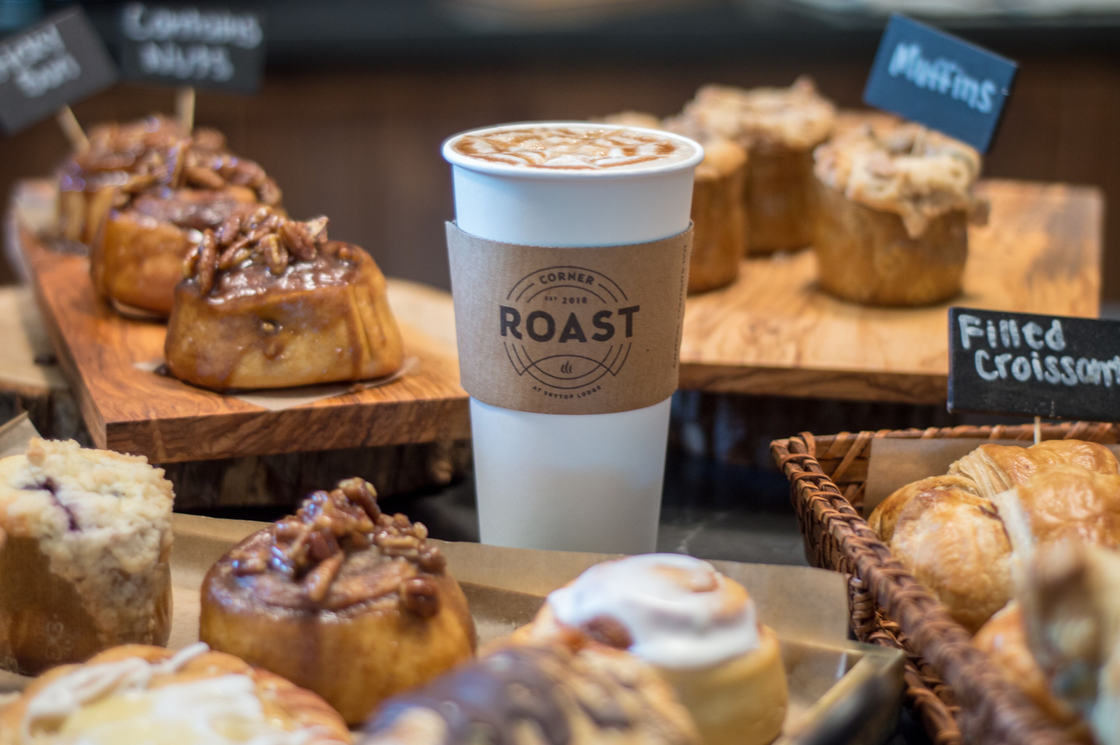 Une variété de pâtisseries et une tasse de café avec une étiquette, présentés sur des planches en bois.