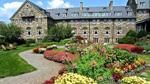 A stone building with multiple windows and a garden with colorful flowers. - Skytop Lodge (Skytop)