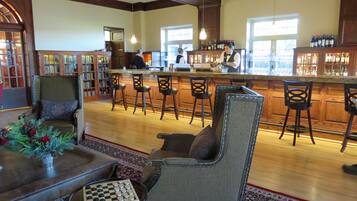 A bar area with wooden furniture, a chess table, and a bar counter with bottles.