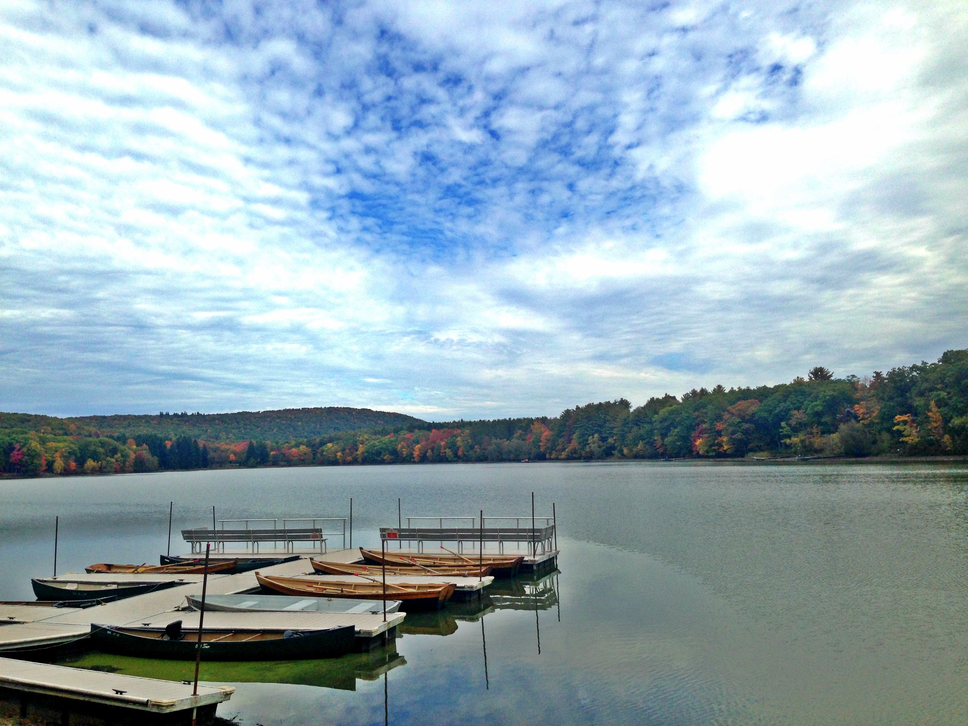 Un lac paisible où plusieurs bateaux en bois sont amarrés à un quai.