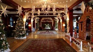 A grand lobby with a central table, Christmas trees, and star decorations. - Skytop Lodge (Skytop)