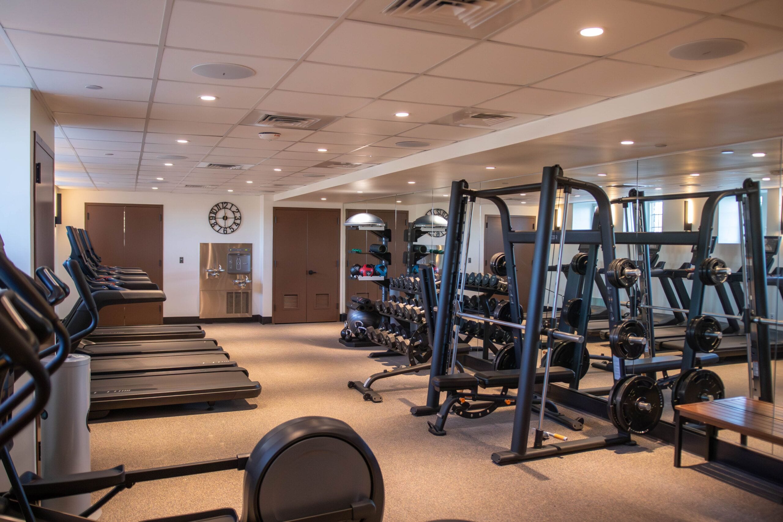 Ein Fitnessstudio mit Laufbändern, Krafttrainingsgeräten und Kurzhanteln.