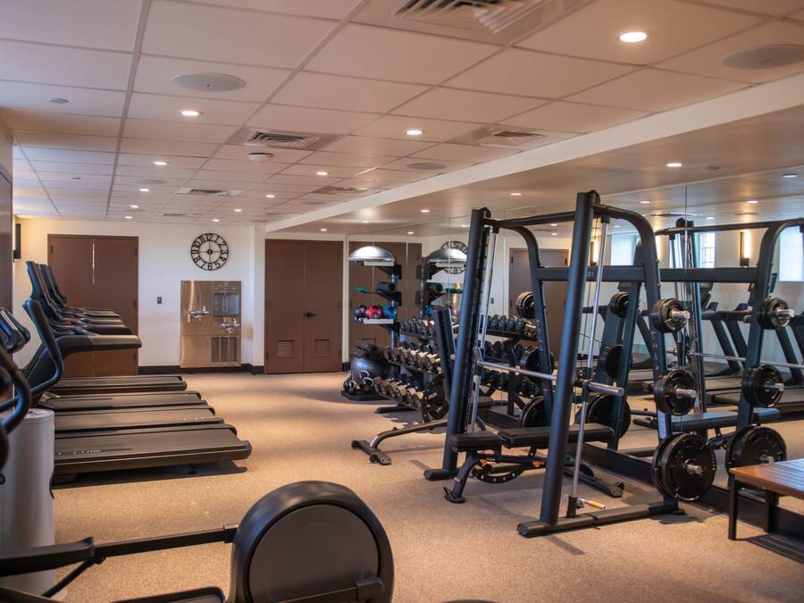Ein Fitnessstudio mit Laufbändern, Krafttrainingsgeräten und Kurzhanteln.