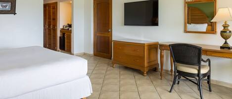 A hotel room with a bed, a desk, a chair, a television, a wardrobe, and a mirror.