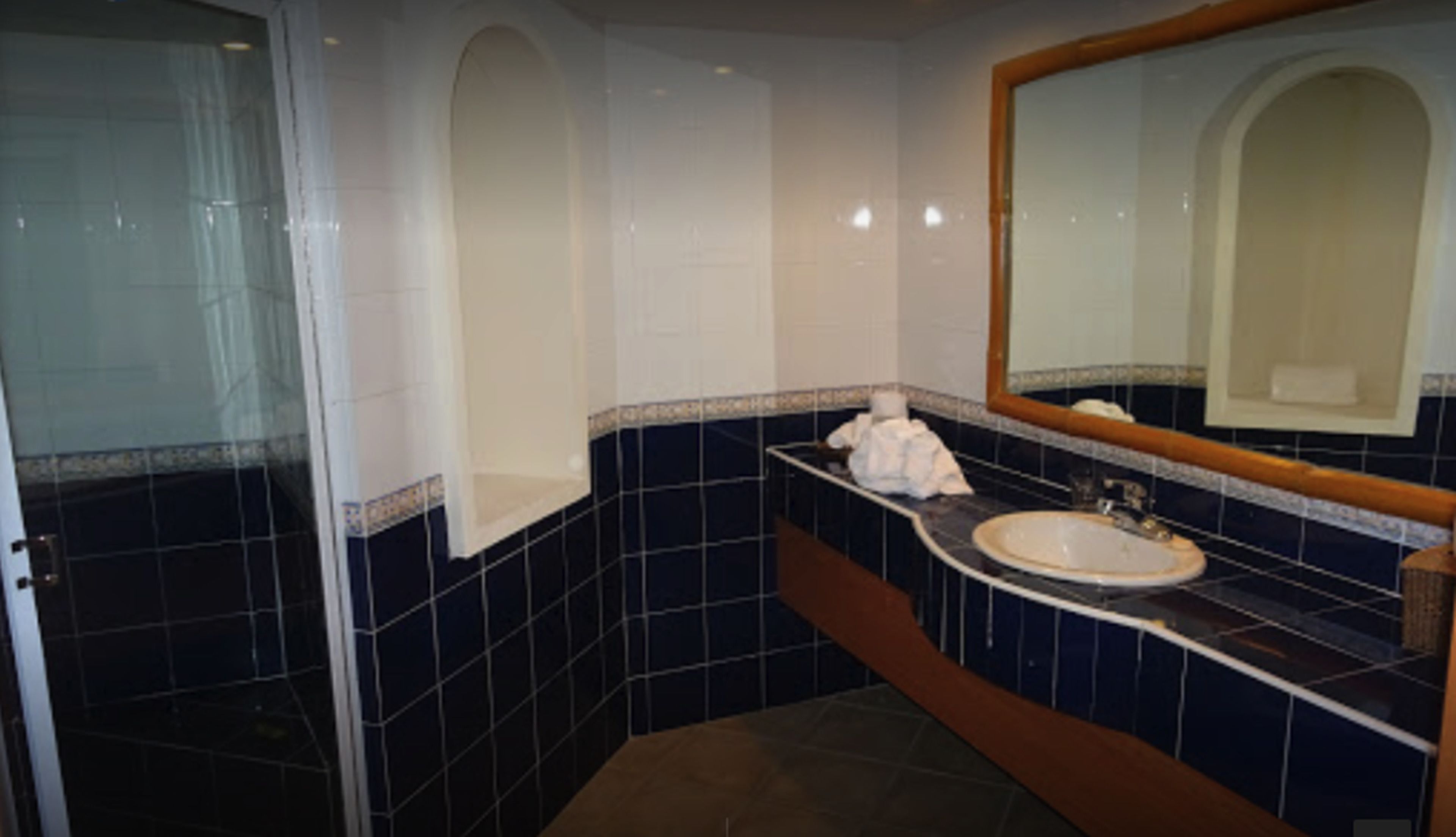 A bathroom with a sink, mirror, and tiled walls.