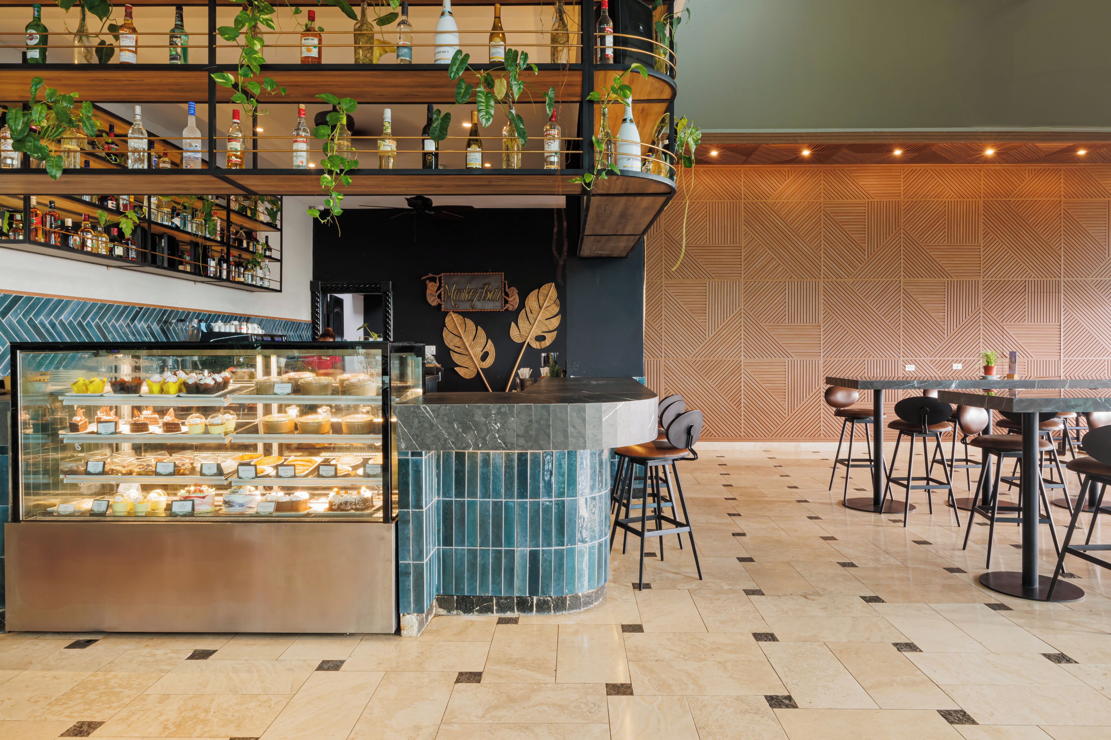A modern bar area with a curved counter, a display case of desserts, and seating arrangements.