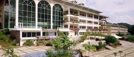 A hotel with multiple balconies, a swimming pool, and a waterfall feature.