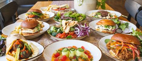 A table with various dishes including burgers, salads, and a plate with a meatball.