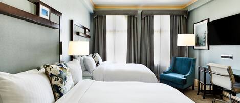 A hotel room with a large bed, two bedside tables, a desk with a chair, and a TV mounted on the wall.
