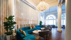 A spacious living area with a teal sectional sofa, a round coffee table, and a chandelier. - Hotel Shattuck Plaza (Berkeley)