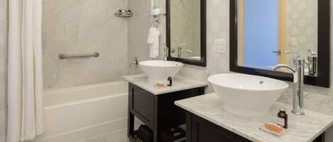 A bathroom with two sinks, a bathtub, and a large mirror.