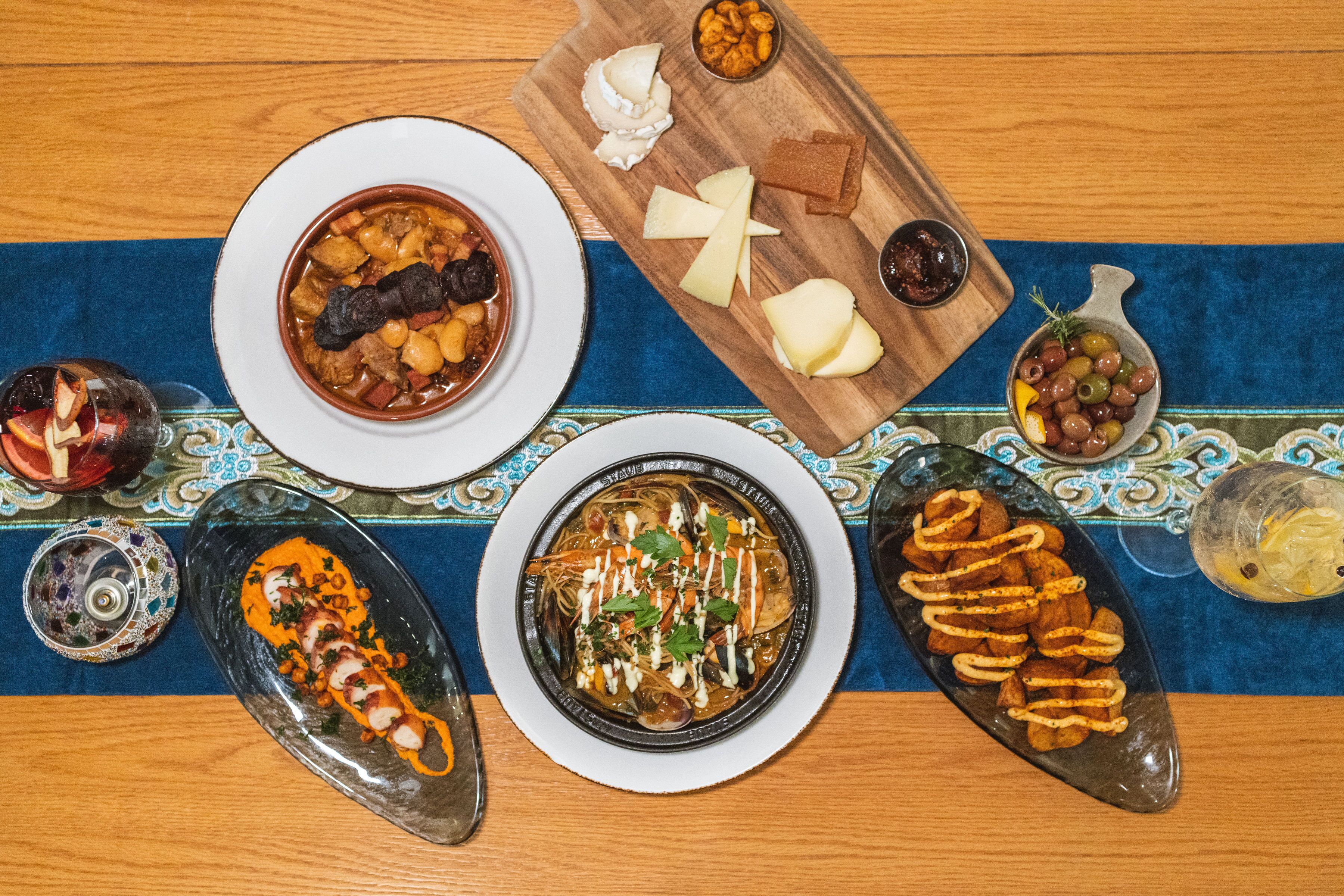 A variety of dishes on a wooden table with a blue cloth runner.