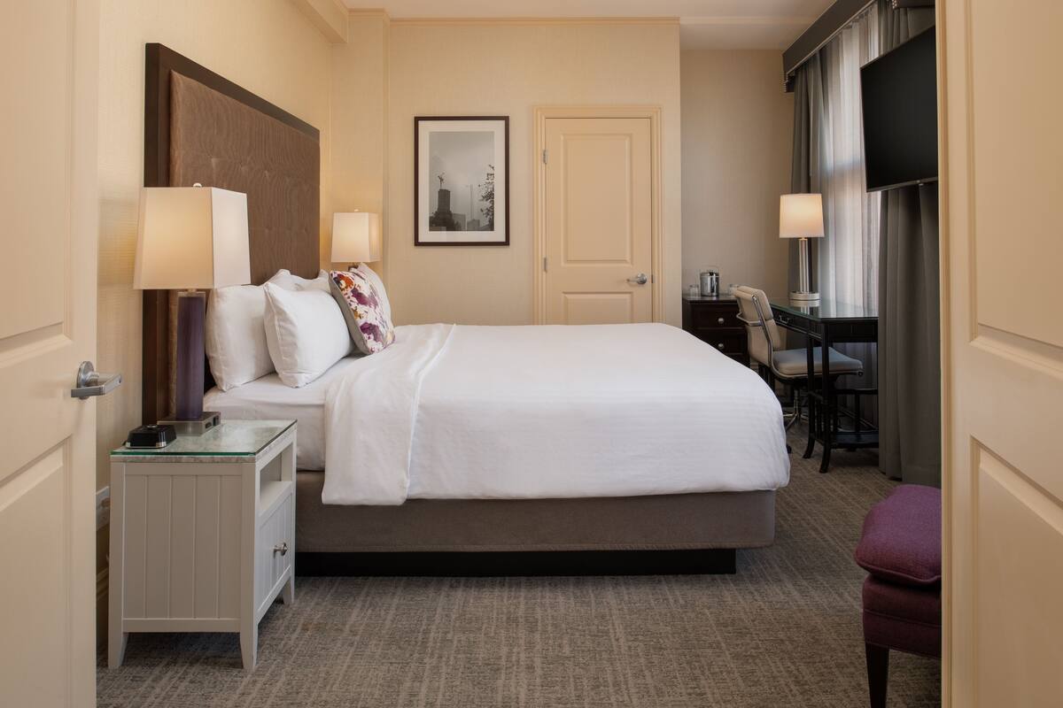 Una habitación de hotel con cama, mesitas de noche, escritorio y silla.