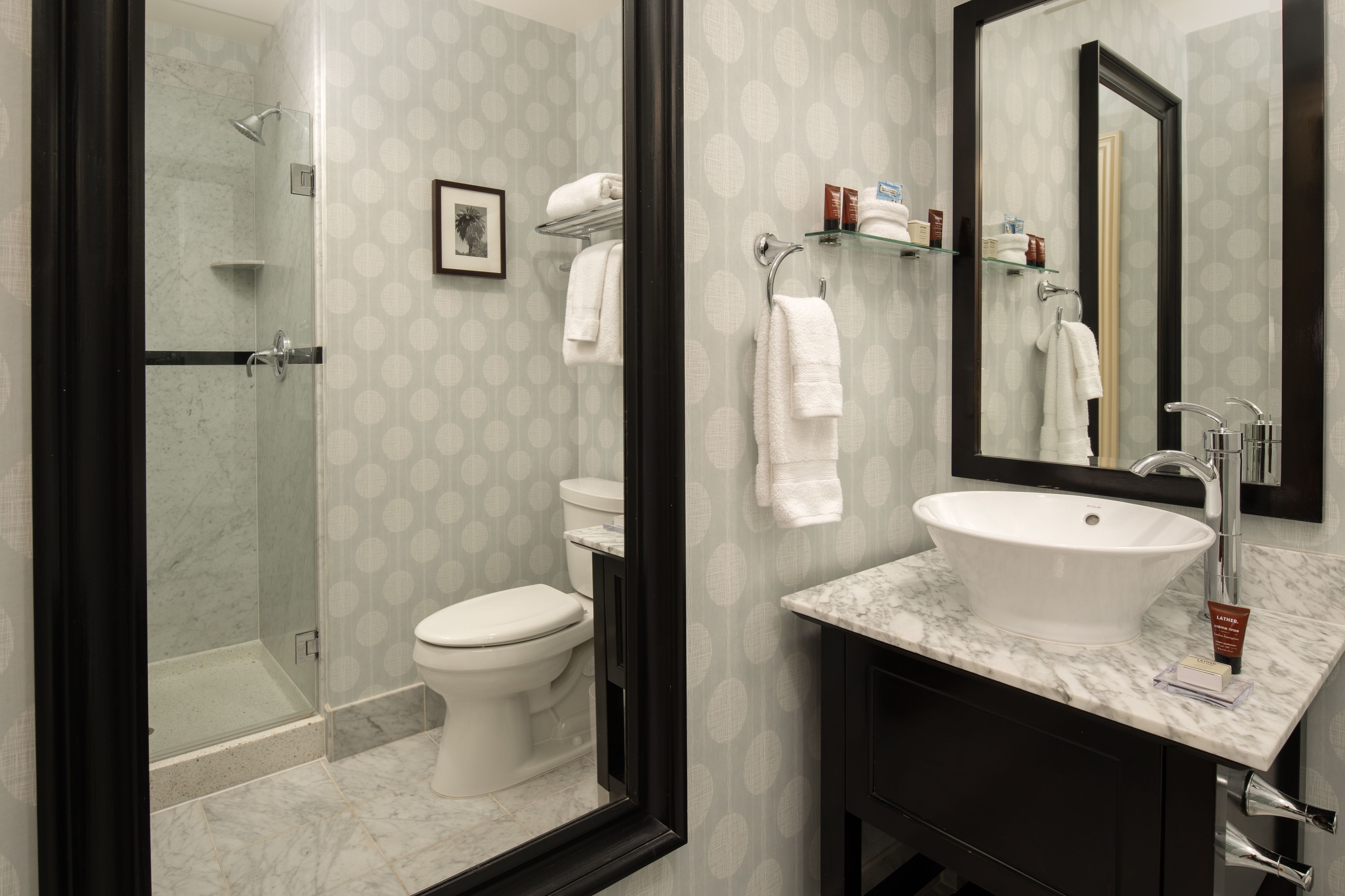 A bathroom with a shower, toilet, sink, and a large mirror.