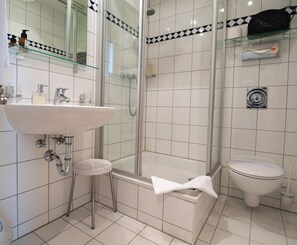 A modern bathroom with a glass shower enclosure, a white sink, and a toilet. - Hotel Martha Dresden (Dresden)
