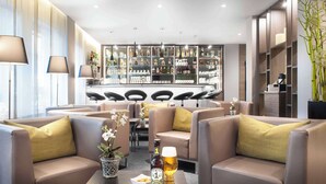 A modern bar area with leather sofas, a bar counter, and a variety of liquor bottles. - Best Western Hotel Favorit (Ludwigsburg)