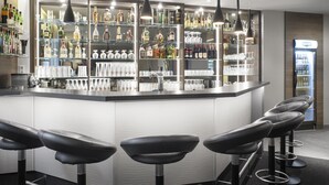 A modern bar area with a central island, bar stools, and a variety of liquor bottles and glasses. - Best Western Hotel Favorit (Ludwigsburg)