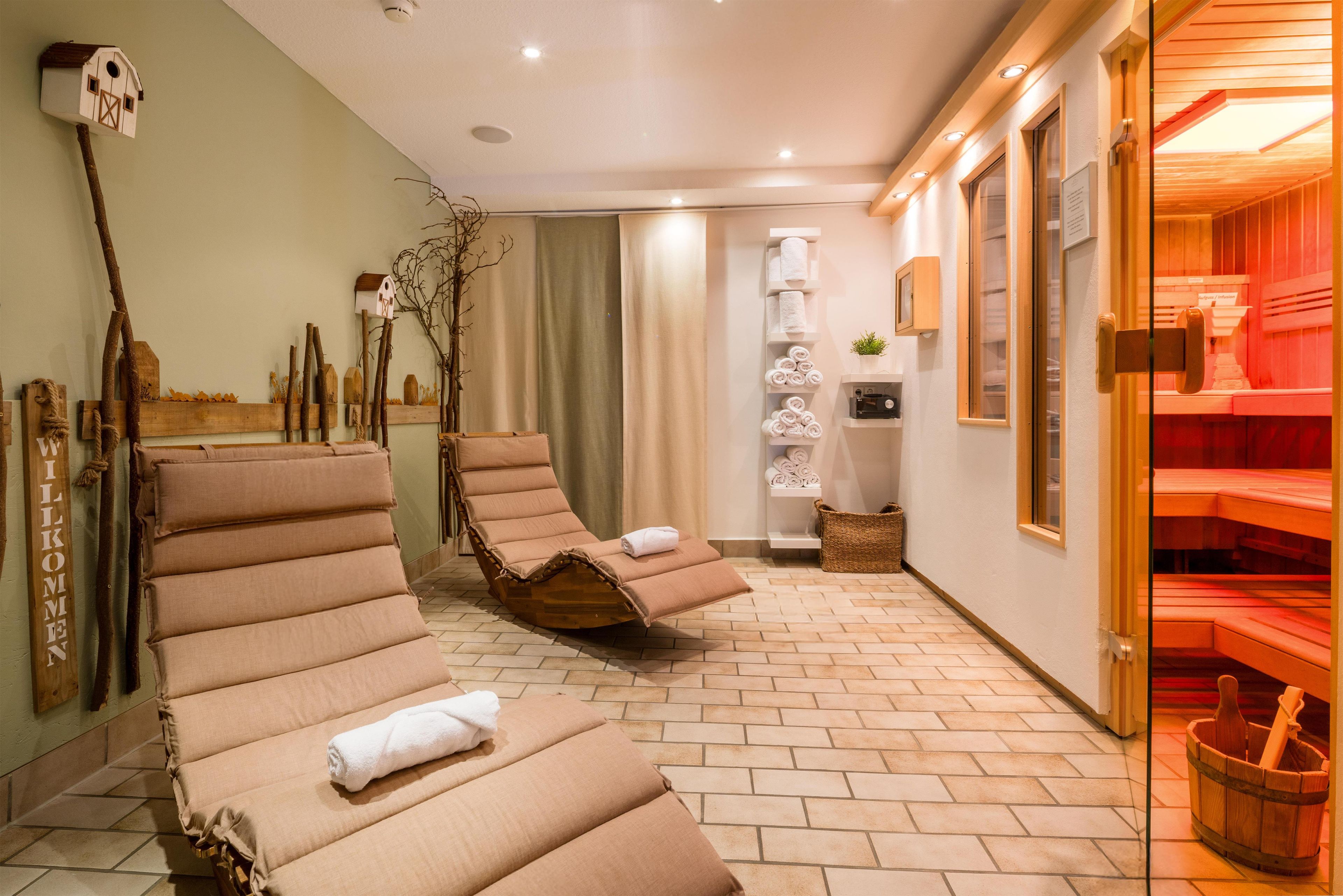 Un cuarto de spa con dos sillones reclinables, un balde de madera y un perchero para toallas.