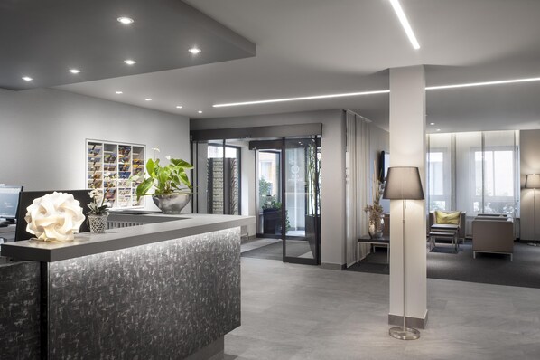 A modern reception area with a desk, a plant, and a bookshelf. - Best Western Hotel Favorit (Ludwigsburg)