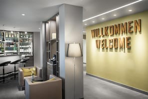 A modern reception area with a bar, seating, and a wall displaying 'WILKOMMEN WELCOME'. - Best Western Hotel Favorit (Ludwigsburg)